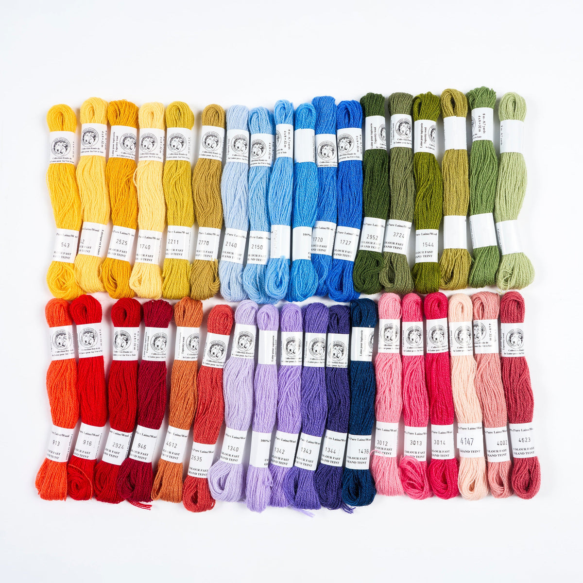 A set of 24 skeins of embroidery floss arranged in a neat 4x6 grid. The colors span the entire spectrum, including reds, oranges, yellows, blues, purples, pinks, greens, and browns, each with a white paper label.
